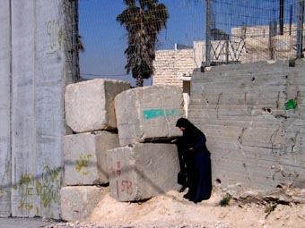 Une femme vient d’emprunter une étroite brèche entre les blocs de béton. - 37.6 ko Une femme vient d’emprunter une étroite brèche entre les blocs de béton. - 37.6 ko